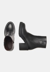 Black ankle boots made of smooth leather, featuring a rounded toe, block heel, side zipper, and a small tag on the heel.