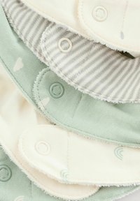 Vier elkaar overlappinge stoffen doeken in zachte pastelkleuren: mintgroen, crème en grijs gestreept, met knoopsluitingen en subtiele patronen.