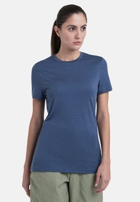 Blå kortærmet T-shirt med rund hals og glat tekstur. Sammen med lysegrønne bukser. Simpel, tætsiddende design.