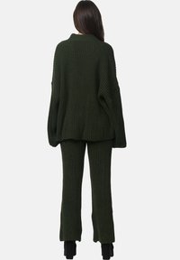 Mörkgrön stickad oversized tröja och matchande utsvängda byxor med ribbat mönster. Setet är designat för komfort med en avslappnad passform.