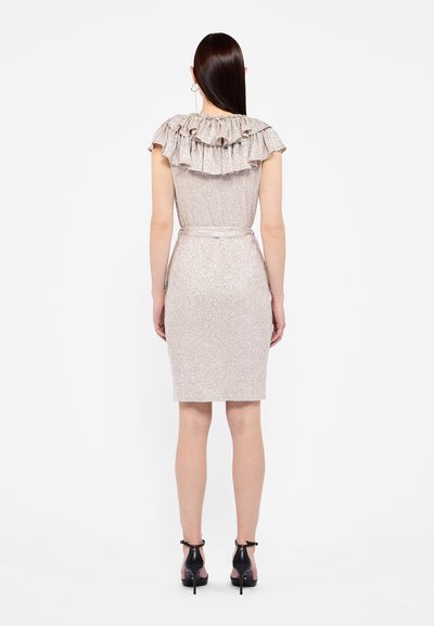 Robe ajustée en tissu rose clair brillant, dotée d'un col froncé, d'une taille ceinturée et d'une jupe fuselée, complétée par des chaussures à talons hauts noires.