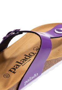 Lilla flip-flop sandal med en blank rem, kork sål og hvid sål. Der er brandlogo og "Fremstillet i Spanien" indgravering på indersålen.