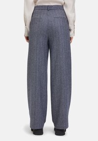 Brede broekspijpen in een herringbonepatroon, met een blauw-witte kleurstelling, achterzakken en een platte tailleband.