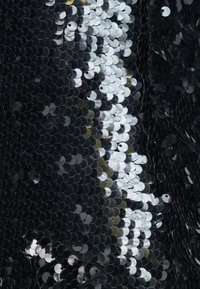 Material din paiete negre cu un amestec de paiete circulare negre lucioase și argintii aranjate strâns, creând o suprafață texturată și reflectorizantă.