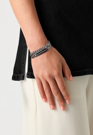 Silver-tone chain bracelet with a flat engraved plate, featuring a smooth metallic finish and interlinked chain design.