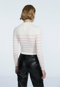 Ribbade långärmade toppar i kräm med rosa horisontella ränder, figurnära passform, hög krage och kontrasterande svarta fusk läderbyxor.