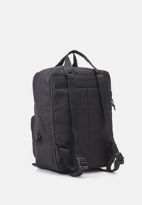 Zaino nero di forma rettangolare, realizzato in tessuto testurizzato. Presenta spallacci imbottiti, tasche laterali con zip e una maniglia superiore.