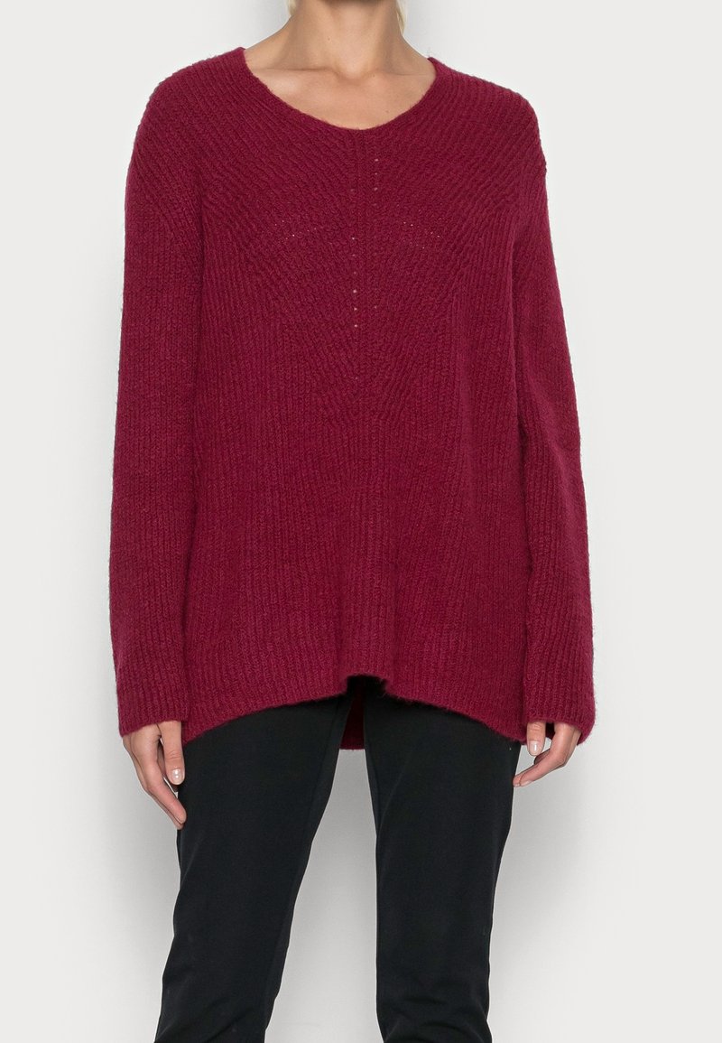 Burgundowa dzianinowa sweter z luźnym krojem, głębokim dekoltem w kształcie litery V, prążkowaną teksturą i długimi rękawami, z podwyższonym tyłem i subtelnymi detalami.