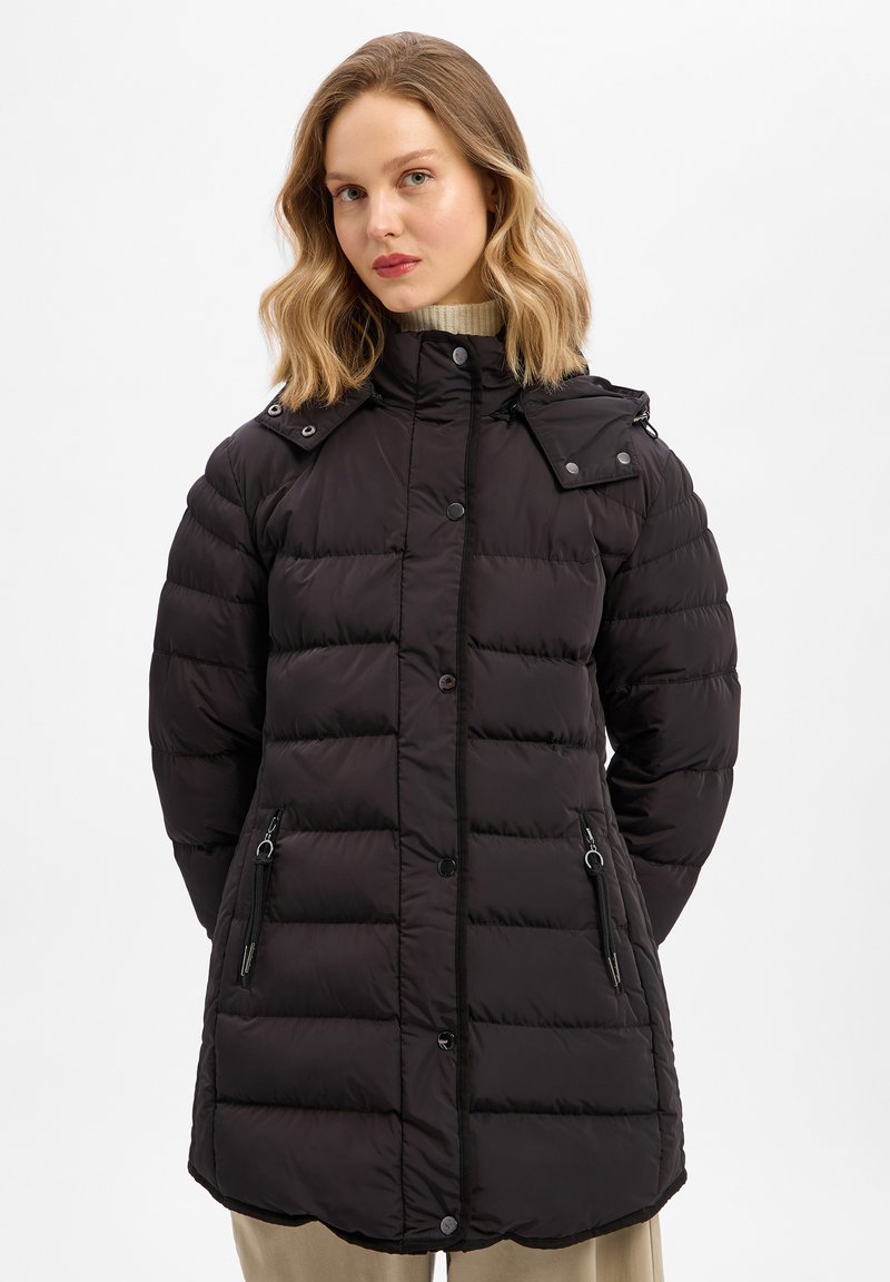 Czarna ocieplana kurtka z wysokim kołnierzem, zamkniętymi kieszeniami na zamek, zatrzaskami i lekko zaokrąglonym dołem. Posiada teksturowaną powierzchnię i przeszycia.