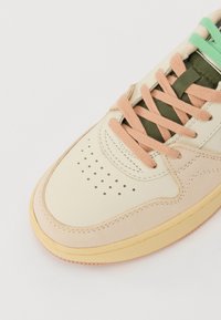 Beżowe skórzane sneakersy z zaokrąglonym noskiem, perforowanymi detalami, pastelowymi różowymi i zielonymi sznurowadłami oraz gumową podeszwą.