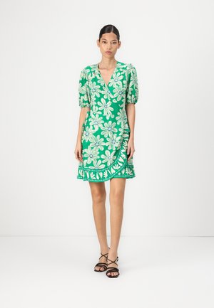 Green floral dress featuring a wrap design, puff sleeves, and a ruffled hem. The pattern includes large white flowers and green accents.