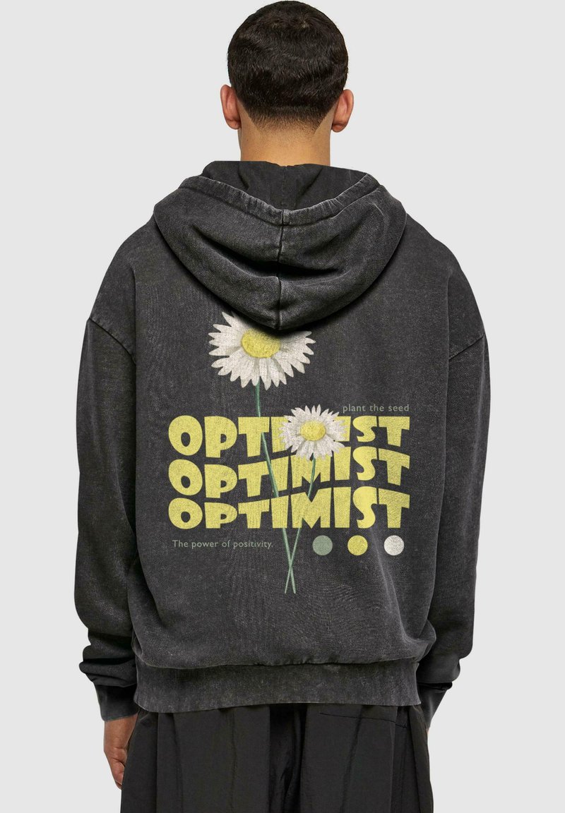 Felpa nera con cappuccio caratterizzata da una stampa grafica di due fiori e la scritta "OPTIMIST" in giallo. Polsini e orlo a coste, vestibilità rilassata, texture morbida.