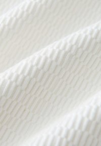 Tessuto bianco strutturato con un motivo geometrico in rilievo, caratterizzato da sezioni alternate lisce e rigate, creando un sottile effetto di profondità.