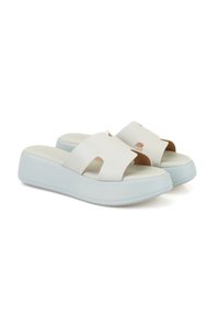 Witte slider sandalen met een gladde synthetische bovenkant en uitsnijdingen. De platformzool is lichtblauw en heeft een gestructureerde onderzijde voor grip.
