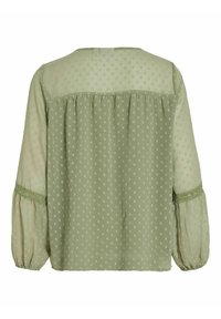Blusa a maniche lunghe, di colore verde chiaro, con motivo a pois, tessuto trasparente e dettagli arricciati sul retro e ai polsini, con finiture in pizzo.