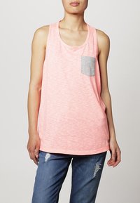 Rosa ärmlös tanktop med en melerad textur, med en grå bröstficka och en avslappnad passform. Matcher med slitna blå jeans.