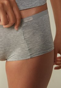 Culottes en mélange de coton gris avec une texture douce, arborant une étiquette logo sur la taille, des coutures lisses et une coupe ajustée.