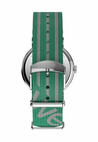 Timex óra zöld szövetpánttal, szürke csíkokkal, ezüst színű fémrészekkel és rozsdamentes acél hátlappal. Kerek számlap látható.