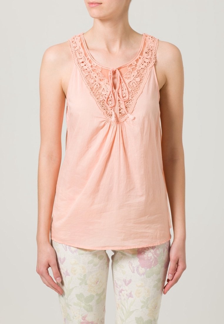 Peach sleeveless top with lace detailing along the neckline and a front tie. Lightweight fabric with a slightly loose fit.