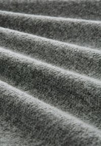 Grau gefilzter Stoff mit strukturierter Oberfläche, der weiche, wellige Falten und subtile Farbvariationen zeigt. Ideal für Polsterungen oder Bekleidung.