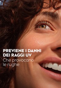 Primo piano di un volto con pelle texturizzata, capelli marroni ricci e un sorriso chiaro. La luce si riflette sulla pelle, mettendo in evidenza toni caldi e dettagli.