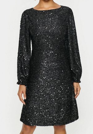 Zwarte jurk met lange mouwen en glinsterende pailletten, licht uitlopende rok en ronde halslijn, gedragen door een staande persoon met ontspannen armen langs het lichaam.