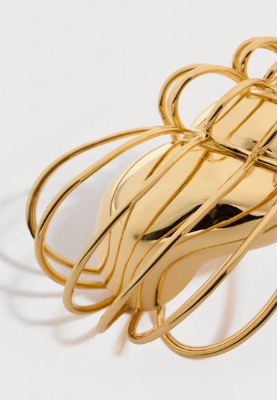 Μεταλλικό κλιπ για τα μαλλιά σε χρυσό με μεγάλο στρογγυλεμένο σχεδιασμό κλουβιού και λείο κέντρο σε σχήμα καρδιάς σε λευκό φόντο.