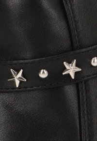 Correa de cuero negro con estrellas y remaches redondos de plata, con una textura suave y detalles de costura visibles a lo largo de los bordes.