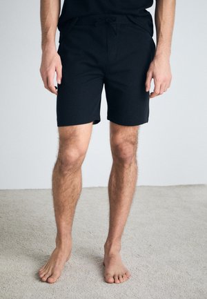 Svarta, shorts i midjehöjd med dragsko i midjan. Tillverkade av mjukt tyg, med en slät yta och utan synliga mönster eller detaljer.