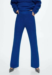 Blauwe gebreide wijde broek met een textuurafwerking, hoge tailleband en een zachte stof. Gecombineerd met puntige metallic hakken.