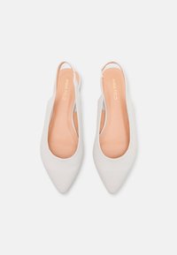 Weiße Slingback-Schuhe mit einer spitzen Zehe, glatter Textur und einer hellbraunen Innensohle. Das Design verfügt über Ausschnitte an den Seiten für Atmungsaktivität.