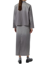 Graue Denimjacke und passende Röcke zeigen einen Farbverlauf von hell nach dunkel. Beide haben eine lockere Passform mit sichtbaren Nähten und aufgesetzten Taschen.