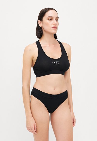 Black sports bra with a scoop neckline and logo print at the center, paired with black, low-rise bikini briefs featuring a textured waistband.