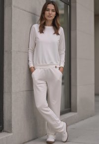 Witte, zachte sweatshirt met een ronde hals, gecombineerd met bijpassende losse sweatpants. Beschikt over zijzakken en een subtiele logo-accent.