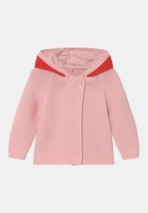 Pink knitted cardigan with a red hood, featuring button closures and ribbed cuffs. The texture is chunky and the design is simple.