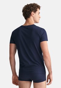 Dunkelblaues T-Shirt mit kurzen Ärmeln aus Baumwolle, mit rundem Halsausschnitt und lockerer Passform, kombiniert mit passenden Shorts.