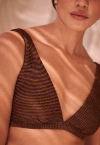 Top bikini a righe marroni con un profondo scollo a V e spalline spesse. Il materiale sembra testurizzato con una leggera lucentezza.