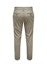 Pantalon en coton beige à la coupe ajustée, avec deux poches arrière à boutons et une finition lisse et texturée.