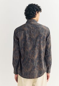 Pikkade varrukatega särk sinise ja pruuni paisley mustriga. Omab nööpidega kinnitatavat kraed ja kaardus ääri. Valmistatud tekstuurse kangaga.