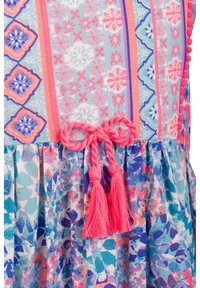 Kolorowa sukienka z mieszanką niebieskich, różowych i fioletowych wzorów, z talią ściągniętą oraz dwoma różowymi frędzlami ozdabiającymi kokardę.