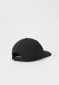 Svart caps med buet visir, laget av stoff. Har justerbar stropp bak og en sirkulær knapp på toppen. Enkel, udekorerte design.