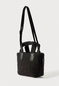 Gequilte zwarte stoffen tas met dubbele handvatten, verstelbare schouderband, leren accenten en een gestructureerd oppervlak. Compact rechthoekig van vorm.