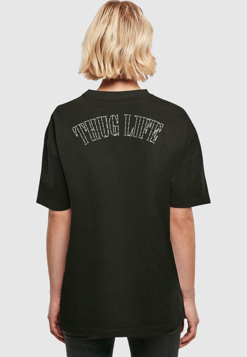 Černé bavlněné tričko s potiskem na zádech, který hlásá "THUG LIFE" křivým bílým prošitím. Krátké rukávy a volný střih.