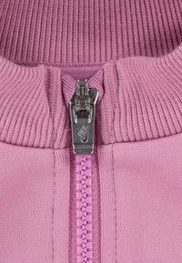 Rosa zip-up plagg med ribbad krage och matchande dragkedja. Dragkedjans dragare har en silverlogotyp. Ytan är slät med ett stickat mönster.