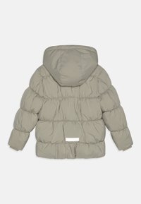 Puffjacka i mjuk grå, med ett kviltat mönster, huva, elastiska ärmslut och en liten vit etikett på baksidan. Slät textur.