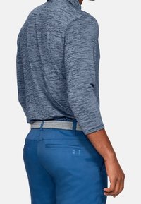 Blaue Sporthose und ein meliertes, navyblaues Langarmhemd mit Kragen. Das Hemd weist ein strukturiertes Muster und eine taillierte Passform auf.