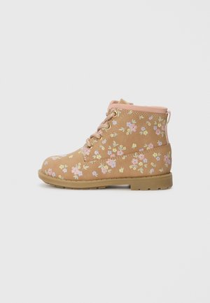 Bota de tobillo color tostado con estampado floral en rosa, morado y amarillo, cordones delanteros, cuello acolchado y suela de goma, mostrada de perfil lateral.