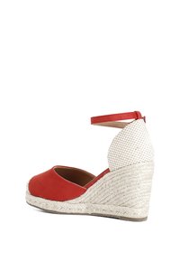 Scarpa con zeppa in tessuto rosso, con retro bianco texturizzato, cinturino alla caviglia e suola in juta intrecciata. Design a punta tonda.