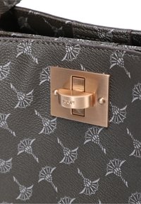 Dunkelgraue, strukturierte Handtasche mit einem goldfarbenen, metallischen Verschluss, auf dem das eingravierte "JOOP!"-Logo sowie ein Muster aus hellgrauen dekorativen Designs zu sehen sind.