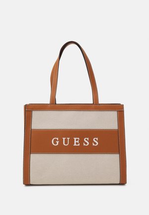 Tan and beige tote bag with white "GUESS" logo; features structured design, dual handles, and contrasting stitching for detail.